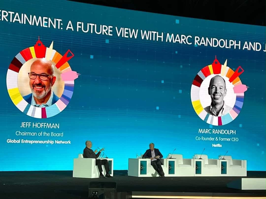 Two speakers in conversation on a conference stage